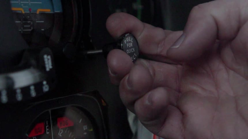 A pilot adjusts knobs in the cockpit