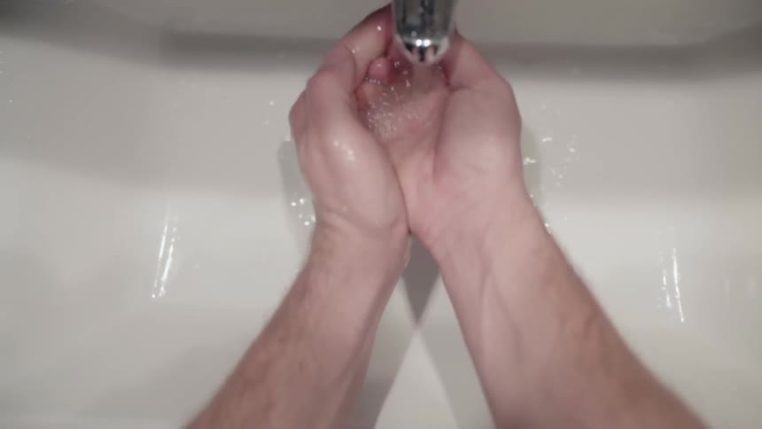 A man is washing his hands and face at a sink