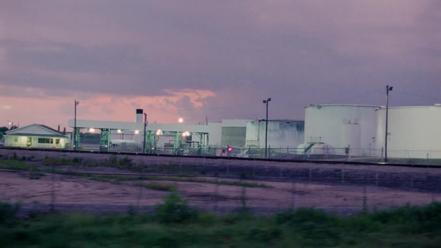 Lights illuminate industrial buildings and tanks