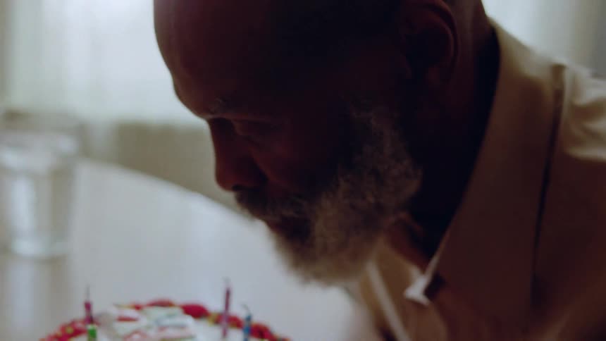 A man blows out the candles on a birthday cake
