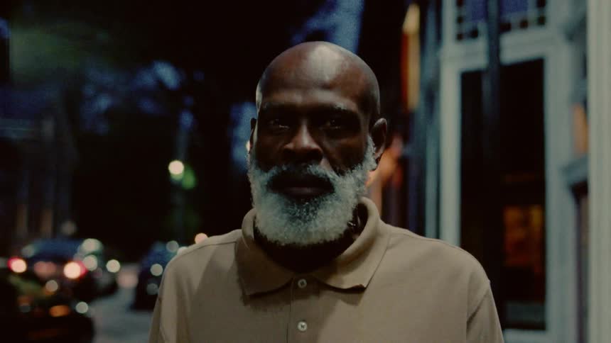 A man walks down a city sidewalk at night