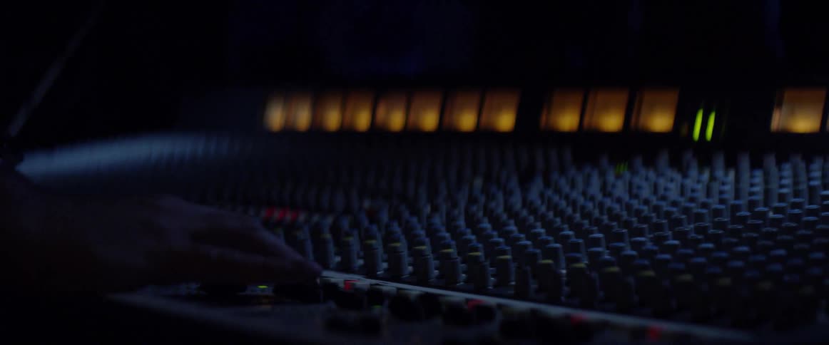 A man adjusts faders and knobs on a mixer