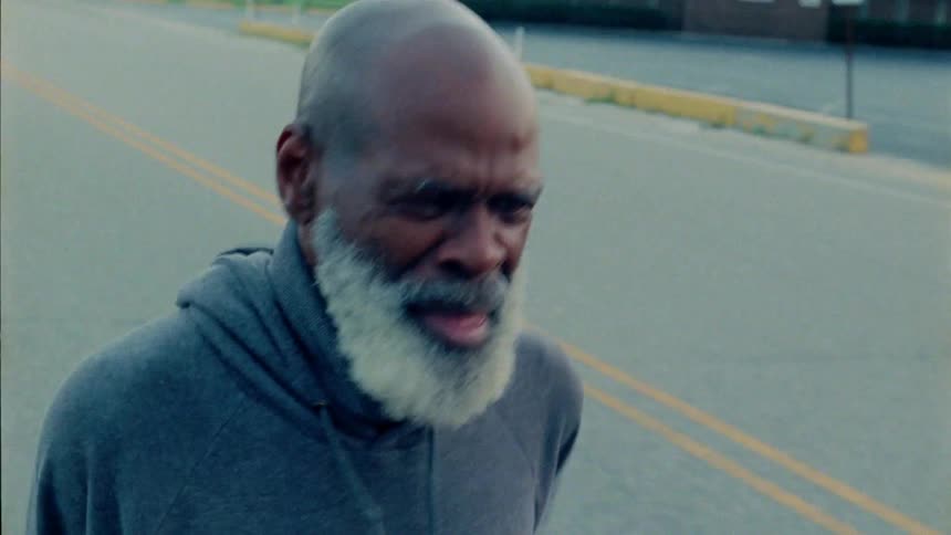 An elderly man jogs out on the street