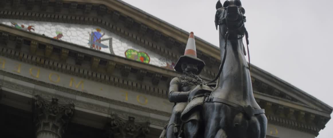 A statue of a man on a horse has a traffic cone on its head