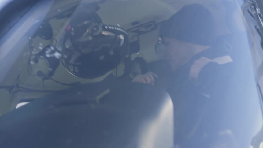 A pilot adjusts himself in a helicopter seat