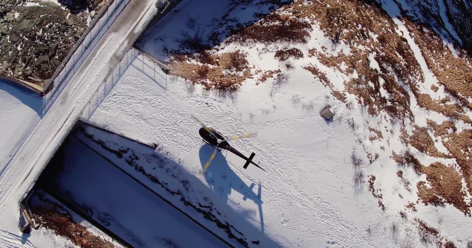 A helicopter takes off from a snowy surface
