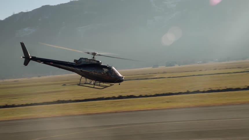 A black helicopter is flying low to the ground forward