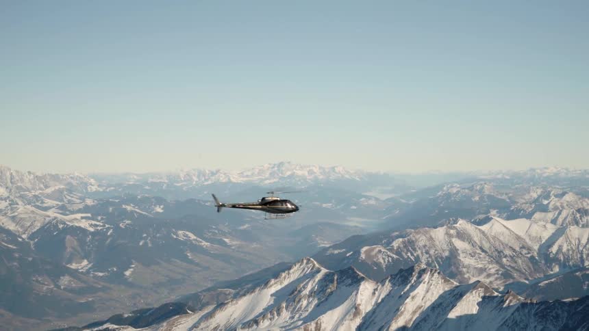 A helicopter is flying above the mountains
