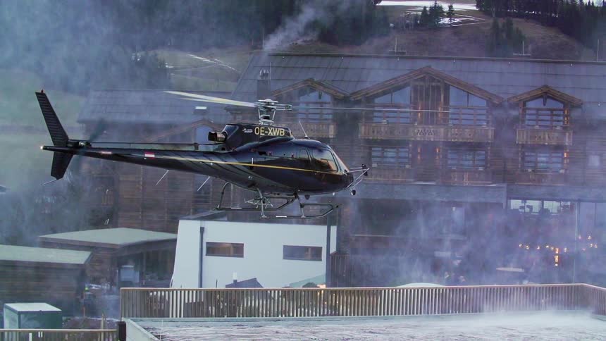 A helicopter is kicking up steam and mist as it hovers over a building