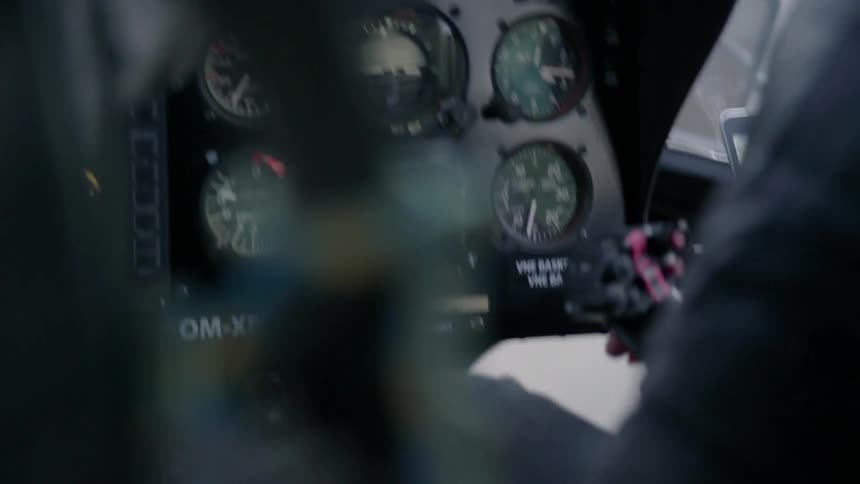 A pilot looks at gauges in the cockpit of a helicopter