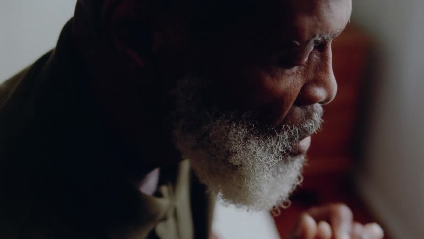 An elderly man puts his hands on his face