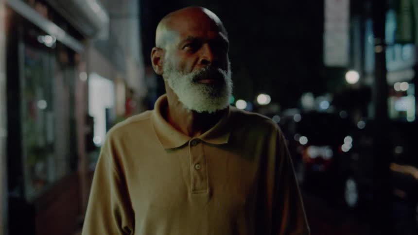 A man walks on a city sidewalk at night