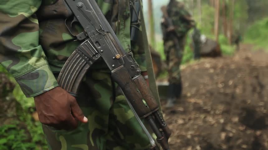 A soldier holds a gun in the forest