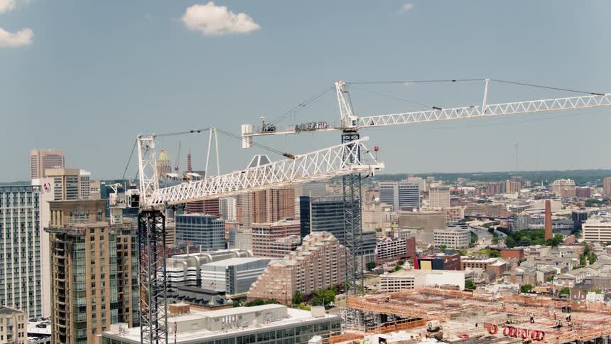 Large white cranes move over the buildings of this city