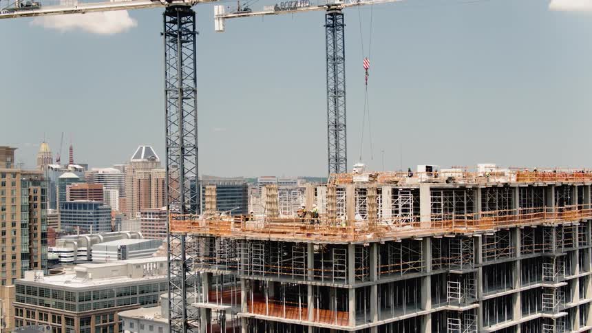 People work at a building construction site under a blue sky
