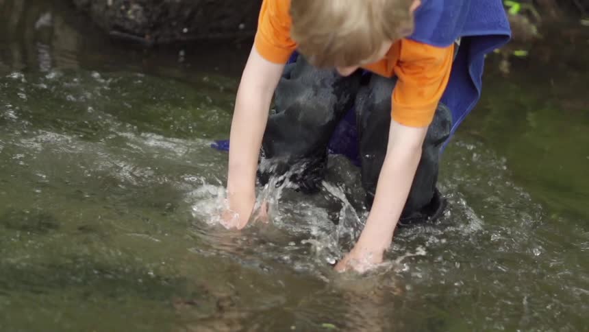 A boy in a cape jumps into a river