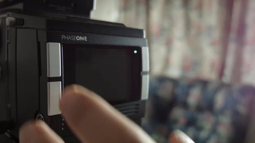 A hand pushes a button on a Hasselblad camera