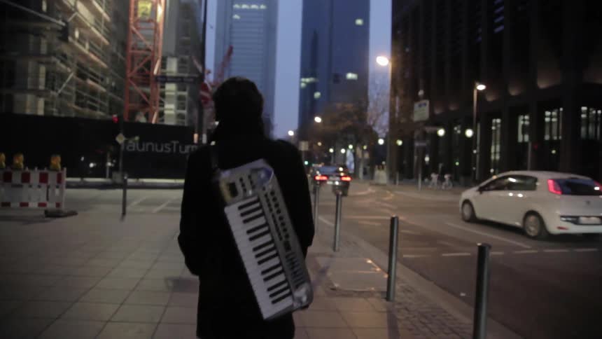 Man walks on city sidewalk with keyboard on his back