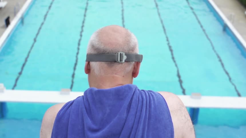 A man wearing goggles stands on a diving board