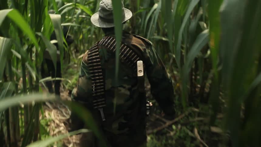 Soldier walks through a green area with a rifle