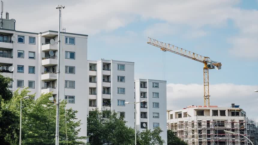 Crane moves around by large white buildings