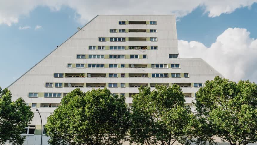 White building with trees in front and clouds passing overhead