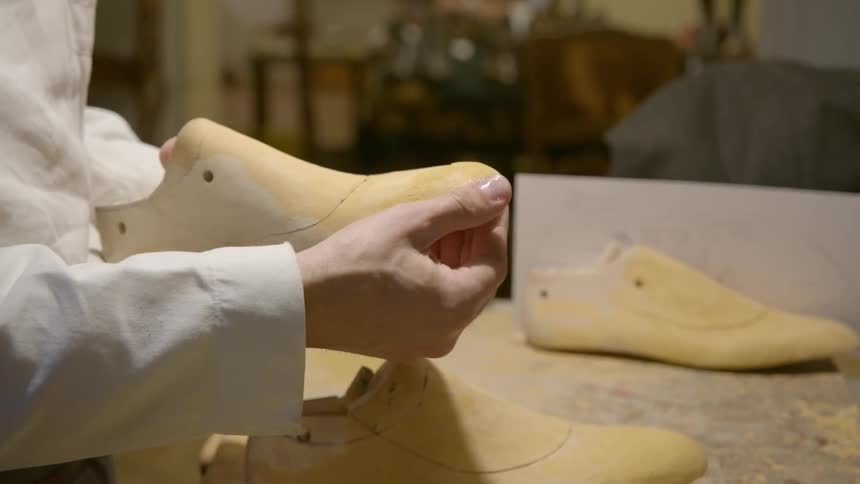 A cobbler constructs shoes in a shop