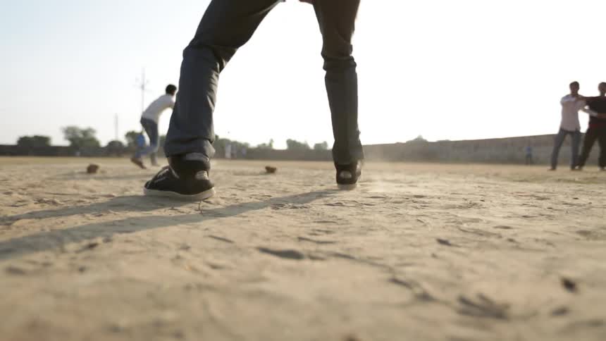 Men play stickball in the dirt