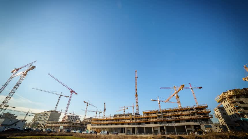 Cranes and workers work on a building in progress