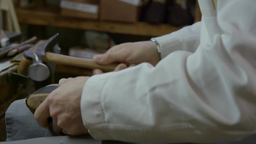 A man is tapping nails into a shoe