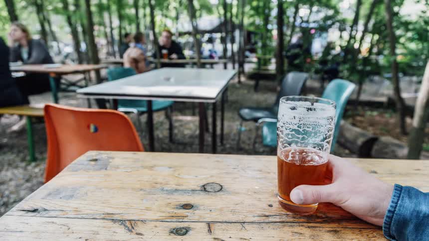 People sitting at tables eating outside as liquid disappears from a cup