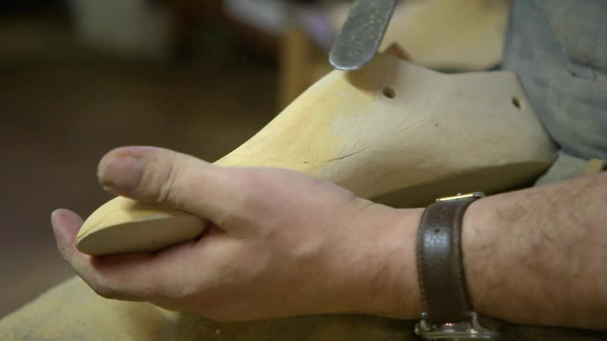 A make is rubbing a wooden shoe