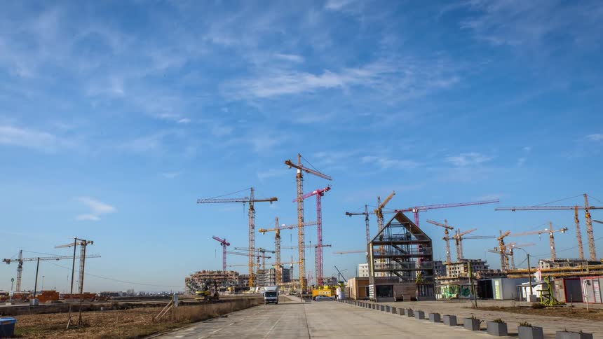 Many cranes help build buildings at a construction site