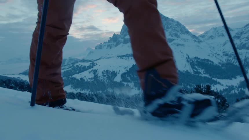 A person hikes through snow with snowshoes