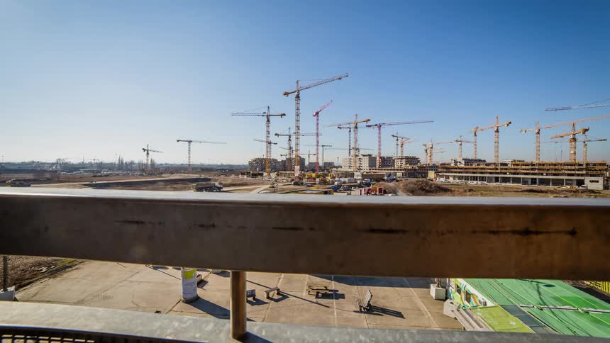 Cranes operate at a construction site on a sunny day