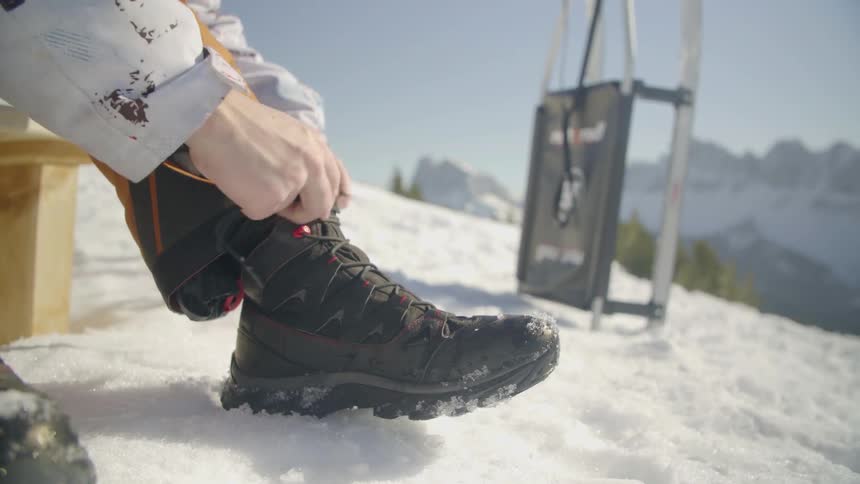 Someone is tying up their boots on a snowy mountain side