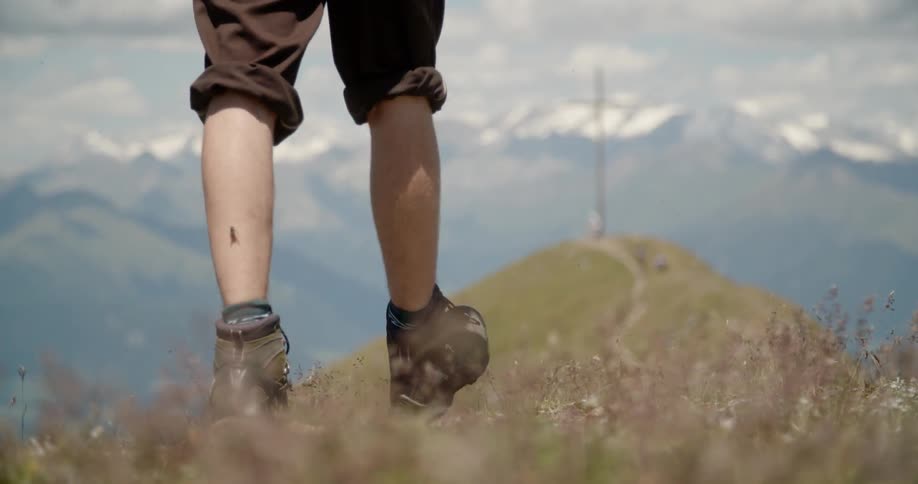 A man hikes up a hill towards a cross