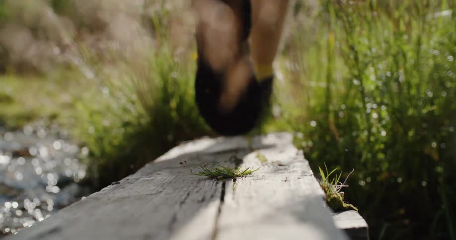 A woman walks over a makeshift stream bridge