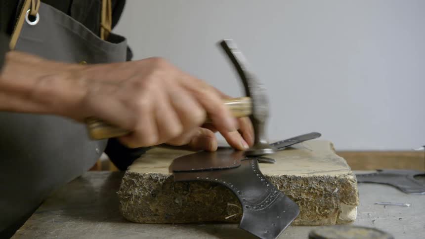 Man tacks two pieces of leather together