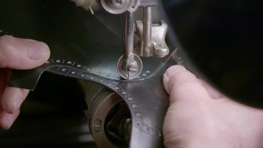 Person guides leather through sewing machine