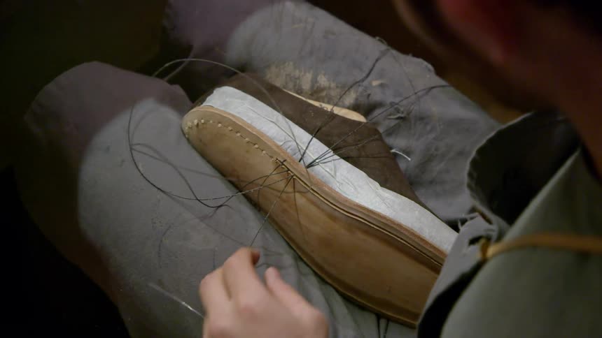 Person sews a sole to a shoe
