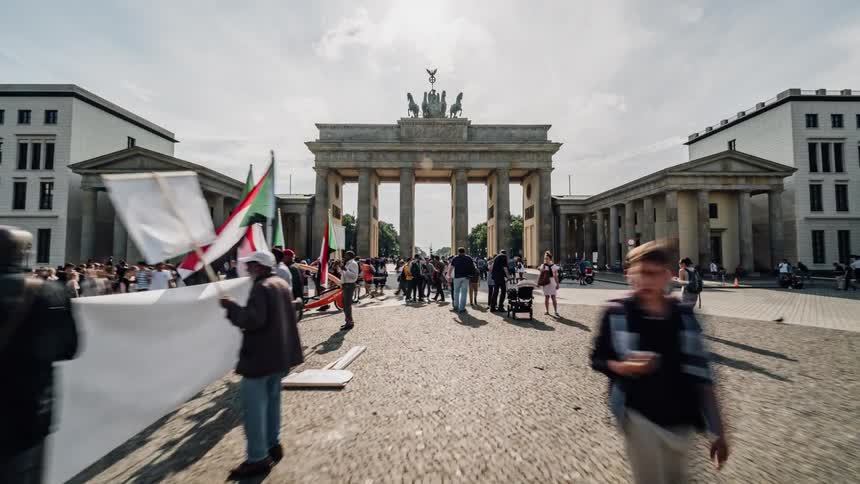 The street is full of people walking around by the monument