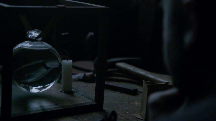 Someone blows out a candle near a glass orb of water
