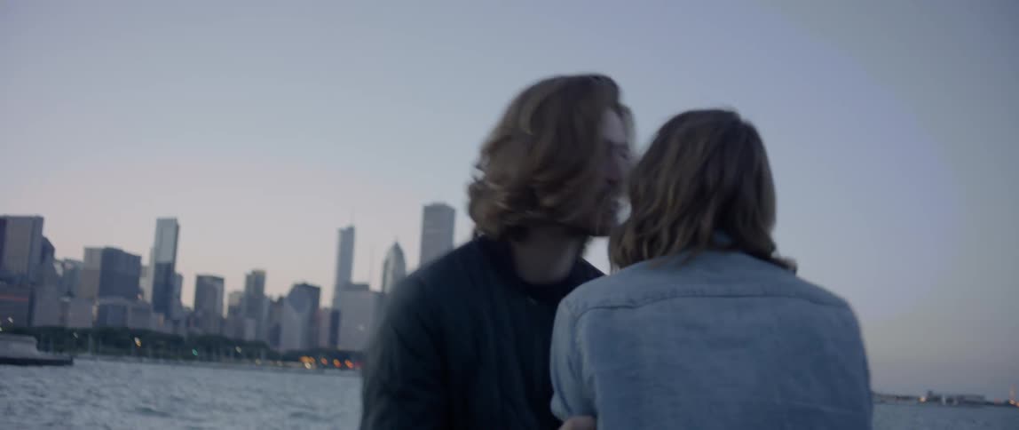 A man and woman stand by the river in new york and kiss