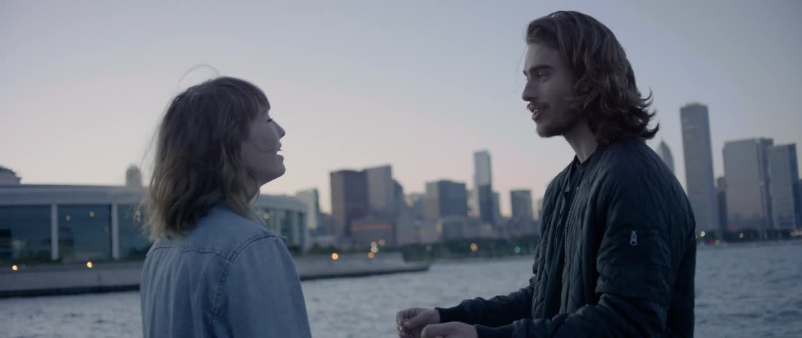 A man and woman talk by the water