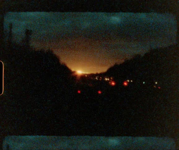 Cars driving down a tree lined street at sunset