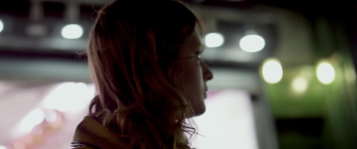 Woman stands next to a building at night