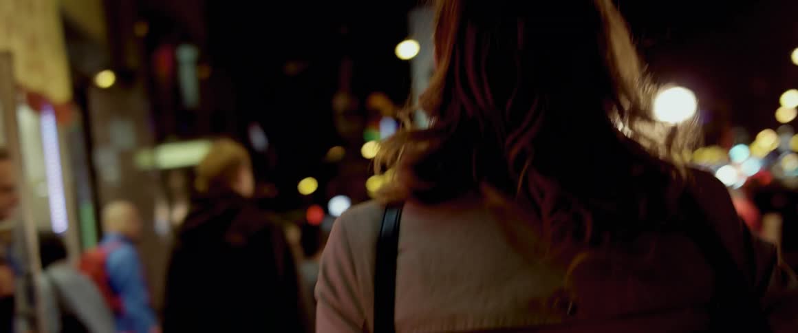 Woman walks on a city sidewalk at night