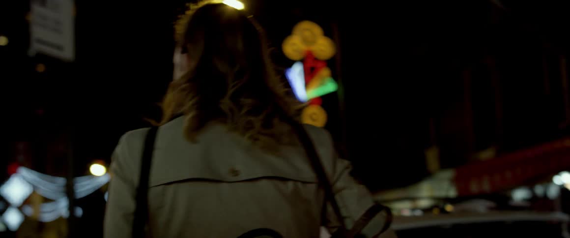 A woman walks down the street at night
