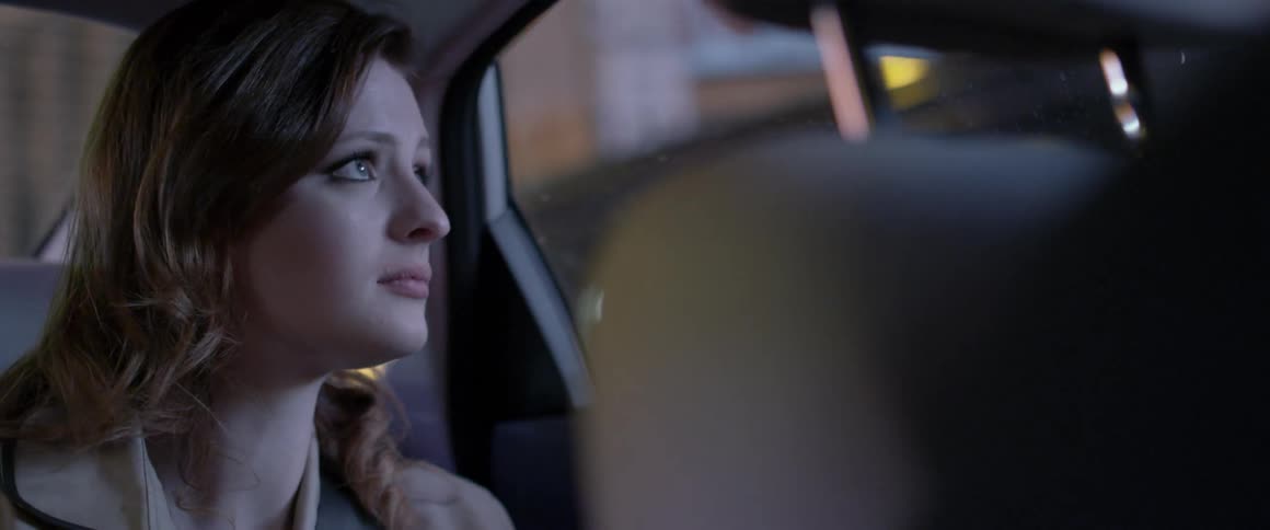 Woman sits in the backseat of a car looking out the window